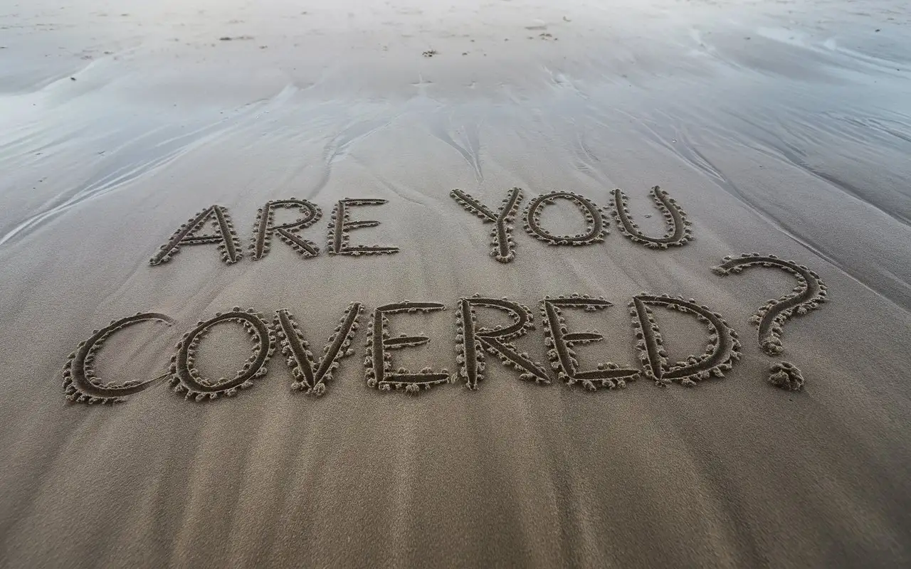 CloseUp-of-Are-You-Covered-Written-in-Damp-Sand-on-a-Beach