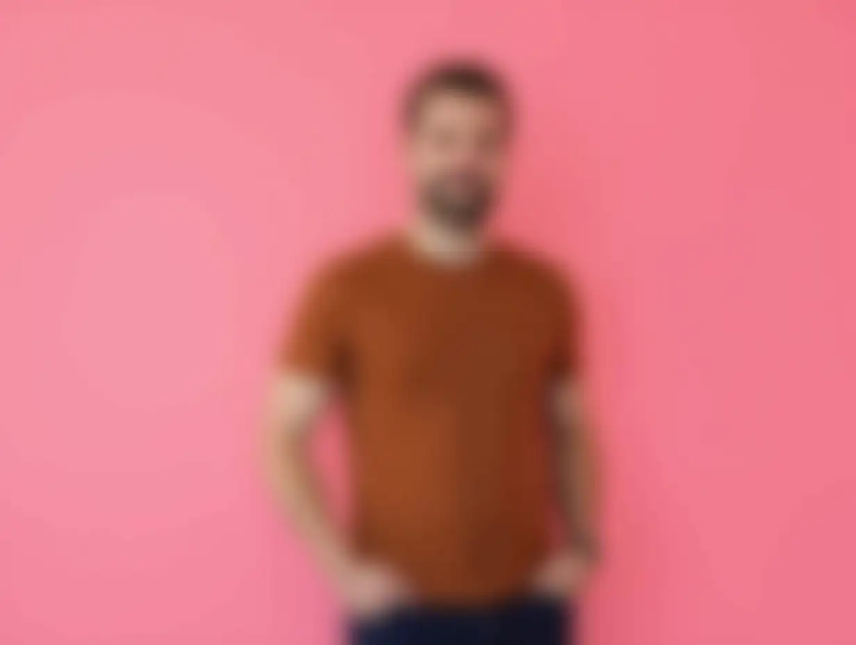 Focused-Man-in-Brown-TShirt-Posing-Against-Pink-Background