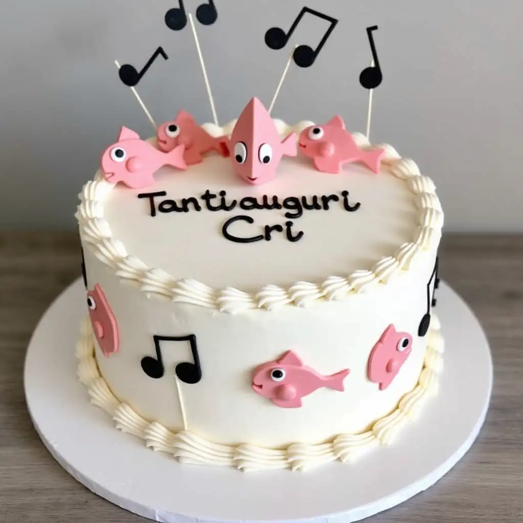 Birthday cake with white, pink and black decorations of fish and music notes saying 'Tanti auguri Cri'