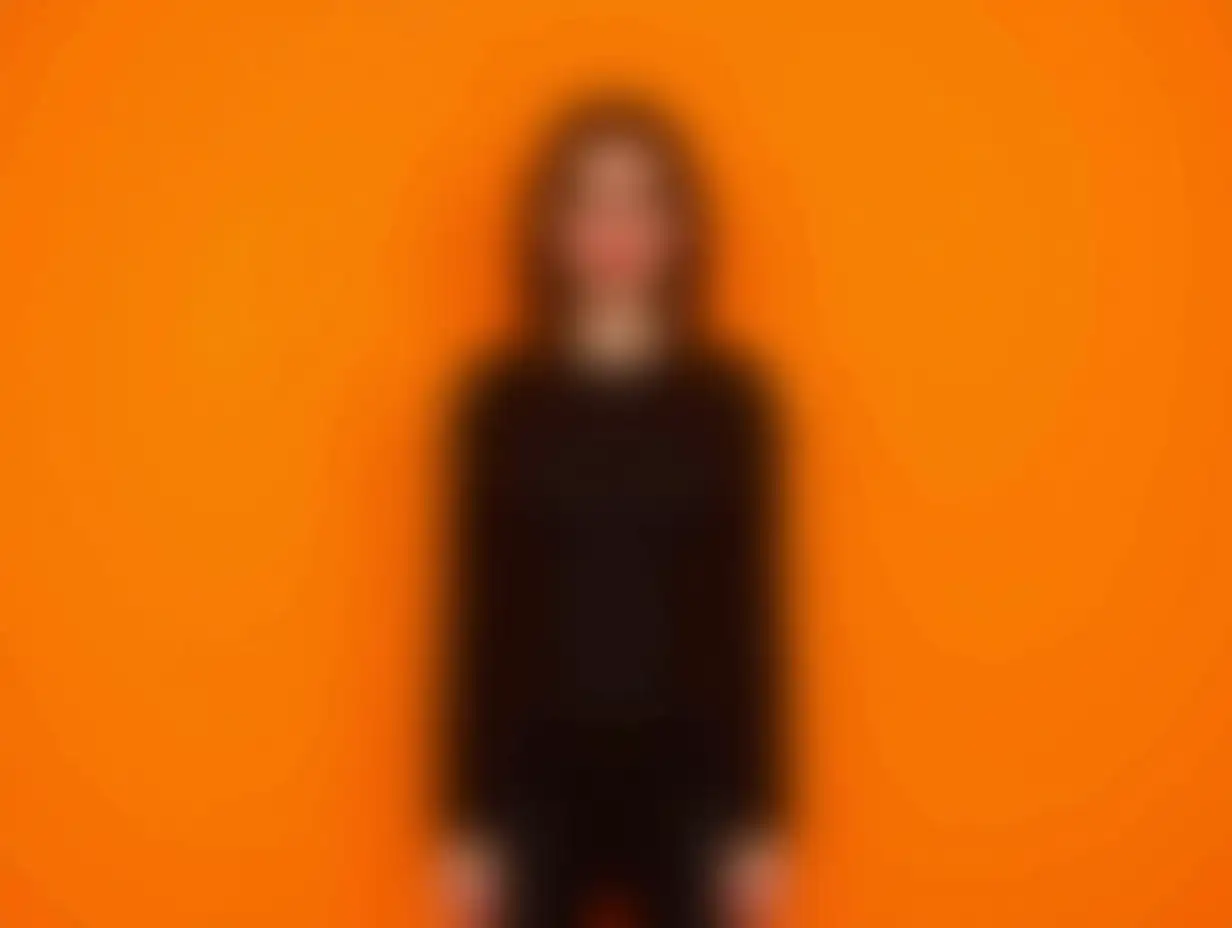 Cute-Girl-in-Trendy-Black-Halloween-Outfit-Staring-at-Empty-Space-on-Orange-Background